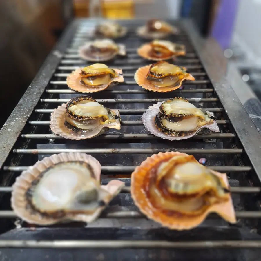 炭火の網の上で焼き上がるヒオウギ貝
